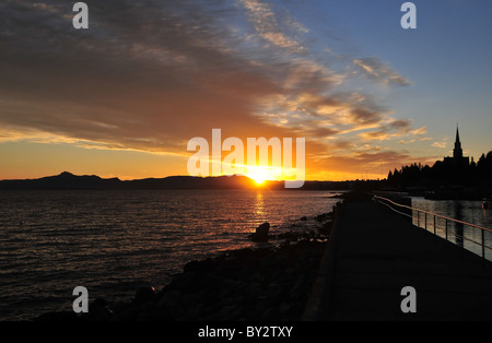 Silhouette vue de la plage, avec le clocher de la cathédrale, du lever de soleil sur les montagnes, Lac Nahuel Huapi, Bariloche, Argentine Banque D'Images