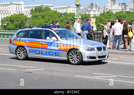 Scène de rue des agents en uniforme dans la région métropolitaine de voiture de police de conduire sur le pont de Westminster avec groupe de touristes au-delà de Londres Angleterre Royaume-uni Banque D'Images