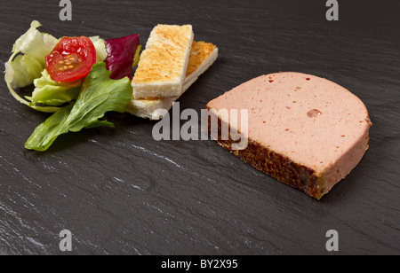 Pate Apetiser avec biscottes soldats et petite salade sur arrière-plan foncé de l'ardoise. Banque D'Images