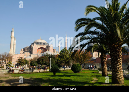 ISTANBUL, Turquie — la basilique Sainte-Sophie vue depuis le parc du Sultan Ahmet, montrant ses dômes, minarets et contreforts distinctifs contre la ligne d'horizon d'Istanbul. L'extérieur du bâtiment reflète à la fois ses origines byzantines et ses ajouts ottomans, avec le dôme central flanqué de quatre minarets ajoutés après sa conversion en mosquée en 1453. Banque D'Images