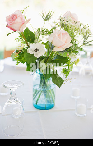 Roses dans un vase sur la table de dîner ensemble avec des lunettes Banque D'Images