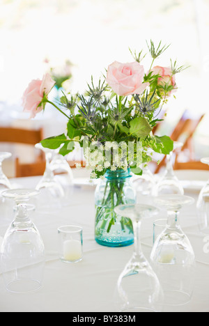 Roses dans un vase sur la table de dîner ensemble avec des lunettes Banque D'Images