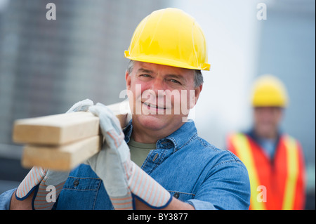 USA, New Jersey, Jersey City, Portrait of construction worker carrying planks Banque D'Images