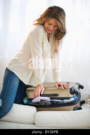 USA, New Jersey, Jersey City, Woman packing suitcase on sofa Banque D'Images