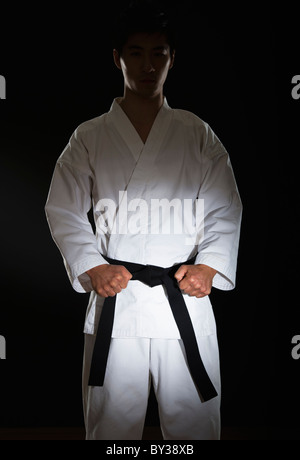 Portrait of young man performing karate position sur fond noir Banque D'Images