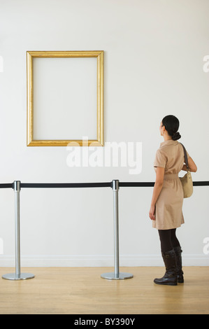 Woman looking at blank en cadre photo art gallery