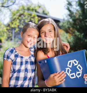 USA, New York, deux filles (10-11, 10-11) holding recycling bin Banque D'Images