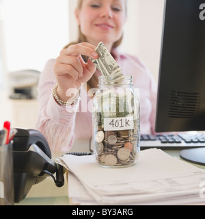 USA, New Jersey, Jersey City, Businesswoman putting money into piggybank Banque D'Images