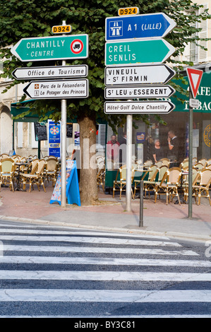 Panneaux de circulation à l'extérieur d'un café sur la route principale de la ville de Chantilly en France Banque D'Images