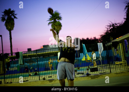 Reedley hallows, California, United States. Un adolescent obèse jette le foot au coucher du soleil. Banque D'Images