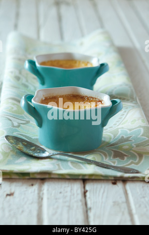 Crème brûlée en bleu ramequins sur une surface blanche rustique Crème brûlée en bleu ramequins sur une surface blanche rustique