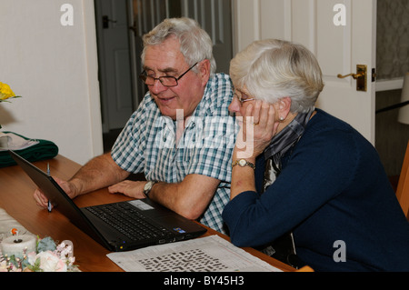 Couple de personnes âgées en utilisant leur ordinateur de Skype amis sur Internet à partir de leur salon Banque D'Images