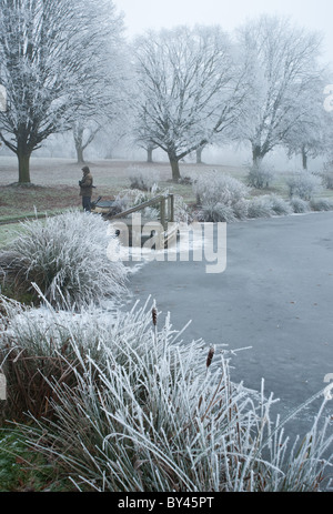 Scène d'hiver dans un lac gelé dans le Warwickshire - personne debout par la jetée. Banque D'Images