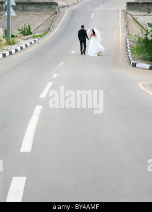 Image conceptuelle de newlyweds walking sur route ensemble Banque D'Images