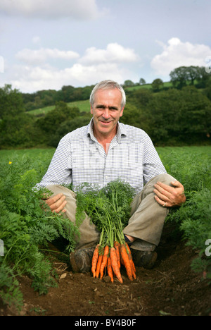 Patrick Holden, directeur de la Soil Association assis dans le champ de légumes avec carottes biologiques. Banque D'Images