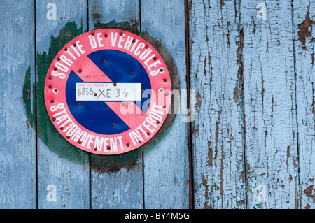 Sortie française 'véhicule' et 'No Parking sign' sur une porte de garage dans un village français. Banque D'Images