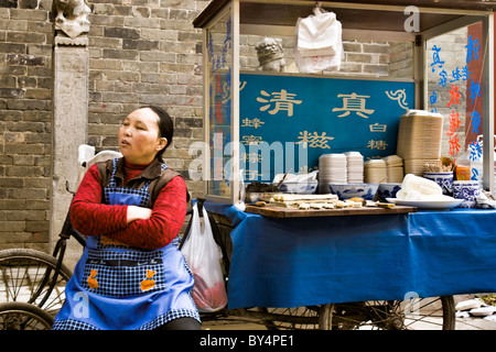 La Chine, XIAN : Chinois femme vendant des aliments préparés dans une ruelle dans le vieux quartier musulman de Xi'an. Banque D'Images