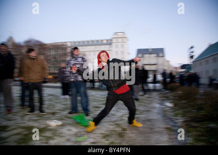 Le centre-ville de Reykjavík, Islande : manifestants protester devant le Parlement islandais. Jeune homme jette des tomates à l'Parli Banque D'Images