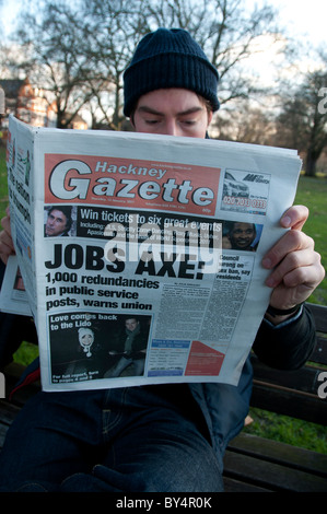 Crise économique de Hackney.Jeune homme lecture Hackney Gazette du Canada et première page, avec l'emploi global à l'ax Banque D'Images