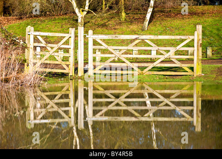 Cinq boisé bar gate reflète dans l'eau d'inondation Banque D'Images