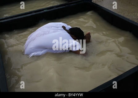 Membre de la communauté chrétienne orthodoxe érythréenne echelle dans le réservoir rempli d'eau du fleuve Jourdain à la cuve baptismale Qaser el Yahud site Kasser aussi Qasser Yehud al ou le nom officiel de la partie occidentale de l'emplacement traditionnel du baptême de Jésus par Jean le Baptiste dans le Jourdain région Vallée de la Cisjordanie Israël Banque D'Images