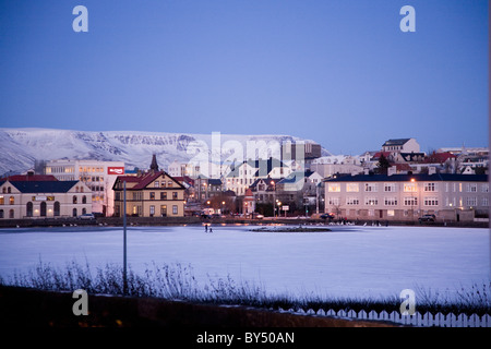 Deux personnes marchant sur un lac Tjornin congelé . Le centre-ville de Reykjavik, Islande. Banque D'Images