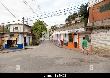 Village-rue tranquille avec peu de piétons chiens errants et aux volets colorés boutiques à soir dans la ville de Puerto Angel Mexique Banque D'Images