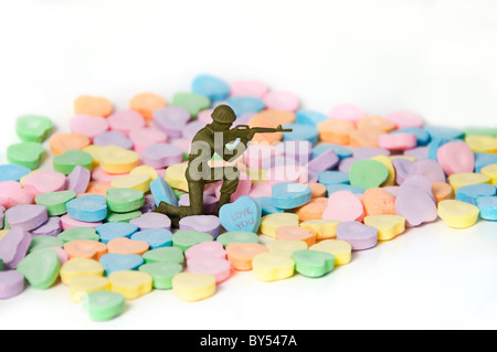 Un soldat de plomb en plastique entouré de bonbons bonbons coeur conversation vise avec son fusil. Banque D'Images