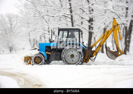 Le tracteur de couleur bleu foncé supprime la neige en park Banque D'Images