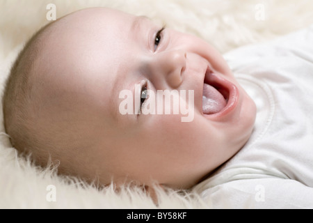 Un heureux bébé couché sur le tapis shag Banque D'Images