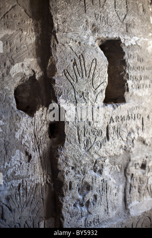 Empreintes de mains et de graffiti manuscrite gravée dans un mur de pierre Banque D'Images