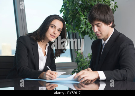 Young businesswoman signature quelques papiers Banque D'Images