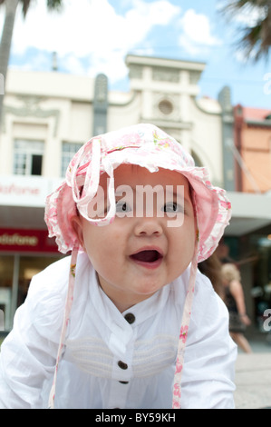 Dix mois baby girl with pink hat smiling et rampants Banque D'Images
