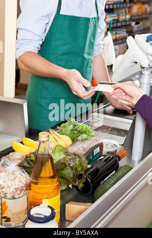 Un client de remettre un chèque d'une carte de crédit au supermarché Banque D'Images