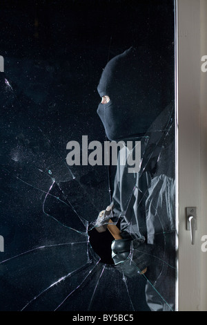 Un casier par effraction dans une fenêtre avec un marteau Banque D'Images