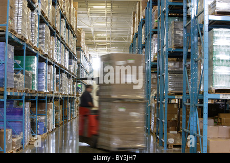 Un chariot élévateur déménagement des palettes de marchandises dans un grand entrepôt. Banque D'Images