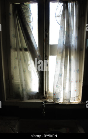 Rideaux de fenêtre et sale dans l'évier de cuisine maison abandonnée. Banque D'Images