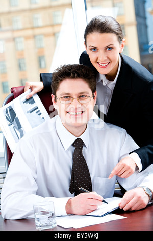 Portrait de deux partenaires d'affaires à la recherche à l'appareil photo avec sourires heureux dans un bureau sur l'arrière-plan de la fenêtre Banque D'Images