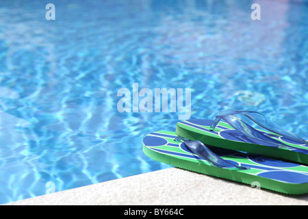 Paire de tongs placé à côté d'une piscine en été Banque D'Images