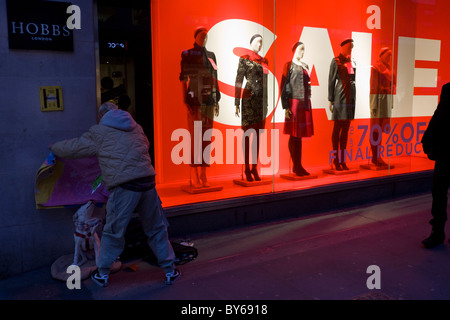 Un gros problème vendeur étend une couverture pour son chien sur le trottoir devant la boutique de vêtements Hobbs, au centre de Londres. Banque D'Images