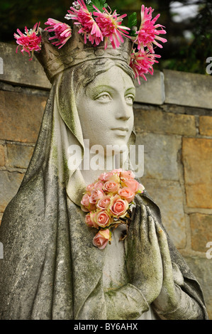 Statue d'un ange avec couronne de fleurs dans un cimetière rural d'Albany. Banque D'Images