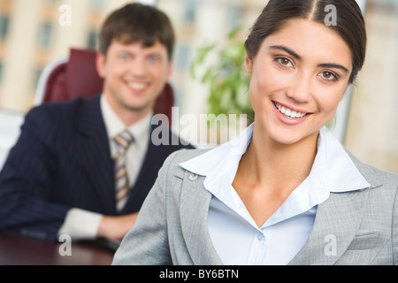 Portrait of happy businesswoman looking at camera sur fond d'homme confiant Banque D'Images