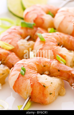 Brochette de crevettes avec des langoustines et le poireau en gros plan sur une plaque blanche Banque D'Images