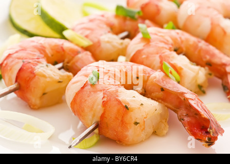 Brochette de crevettes avec des langoustines et le poireau en gros plan sur une plaque blanche Banque D'Images