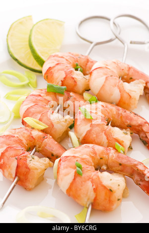 Brochette de crevettes avec des langoustines et le poireau en gros plan sur une plaque blanche Banque D'Images