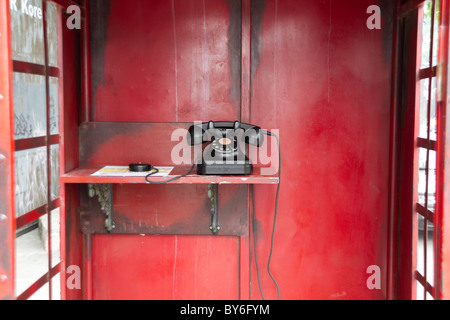 Vieux téléphone dans la cabine téléphonique rouge traditionnel Banque D'Images