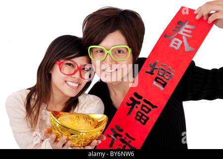 Joyeux Nouvel An chinois. Young couple holding lingot d'or et rouge couplets de printemps Banque D'Images