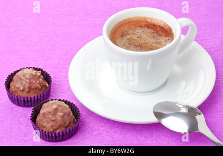 Du café chaud fraîchement préparé en blanc tasse de chocolat au lait et des bonbons à la noisette flakes sur fond rose Banque D'Images