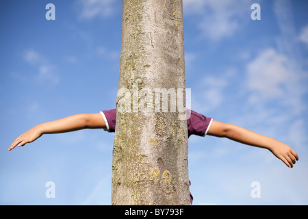 Kid mains derrière un tronc d'arbre Banque D'Images