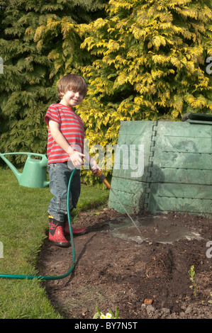 Garçon jouant avec le soutien de faire une flaque d'eau et de boue dans le jardin arrière. quatre-année-vieux Banque D'Images